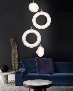 three circular lights hanging from the ceiling above a blue couch in a living room with black walls