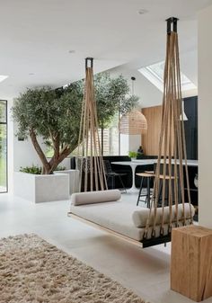 a living room filled with furniture next to a tree in the middle of an open floor plan