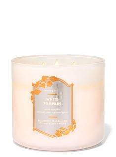 a white candle with an orange label on it