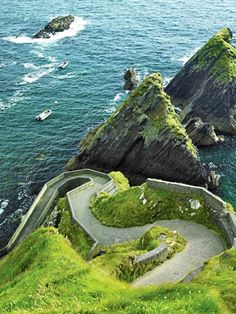 an aerial view of the ocean with two cliffs and a path leading up to it