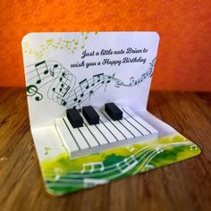 an origami card with music notes and piano keys on it, sitting on a table