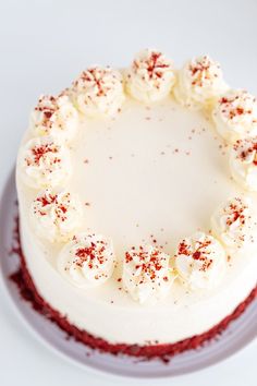 a cake with white frosting and red sprinkles on the top is sitting on a plate