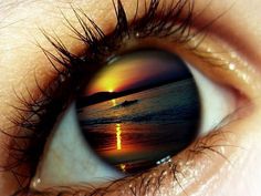 an eye with the reflection of a sunset in it