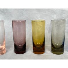 four different colored glass vases lined up in a row