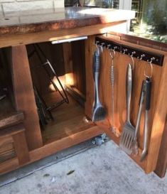 an open cabinet with utensils hanging from it's sides and on the inside