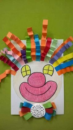 a paper plate with a clown face made out of strips of colored construction paper on it