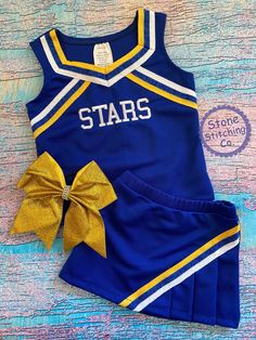 a cheerleader outfit with a bow on the front and side, sitting on a wooden surface