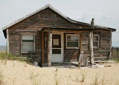 an old wooden house sitting on top of a sandy beach