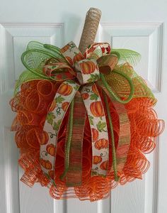 an orange and green mesh wreath hanging on a door