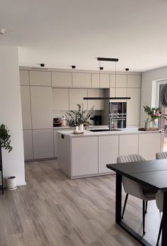 a large kitchen with white cabinets and wooden floors is pictured in this image from the dining room