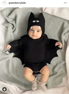 a baby wearing a batman costume on top of a bed