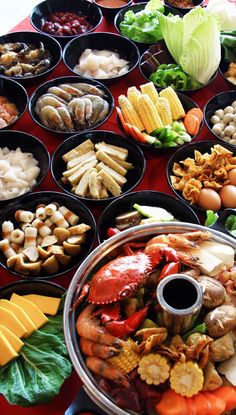 an assortment of food is displayed in bowls on a red tablecloth with other foods