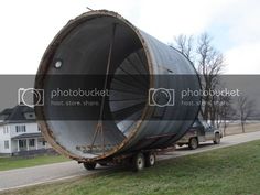 a large metal object on the back of a semi - truck driving down a road