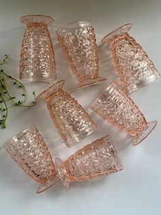 six pink glass goblets sitting next to each other on top of a table