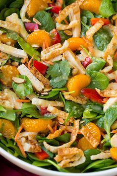 a salad with oranges, chicken and spinach leaves