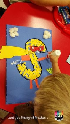 a young boy is drawing on a paper with the number 5 in front of him