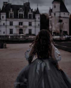 a woman in a dress walking towards a castle