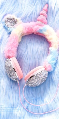 a pair of pink and blue earphones laying on top of a furry surface with unicorn ears