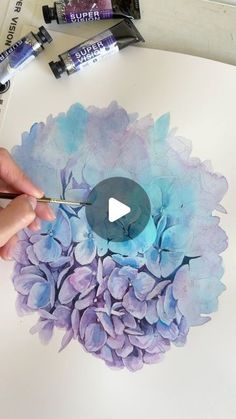 someone is painting flowers with watercolors on paper