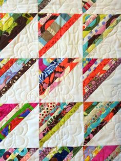 a close up of a quilt on a table topper with many different colored strips