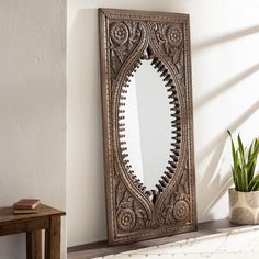 a mirror sitting on top of a wooden shelf next to a potted plant in a room