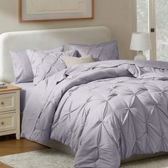 a bed with purple comforter and pillows in a room