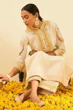 Daisy ivory kurta with gota patti work and highlighted with basra moti. Paired with embroidered hem palazzo.
Component: 2
Pattern: Embroidered
Type Of Work: Gota and Bead Work
Neckline: Mandarin
Sleeve Type: Long Sleeves
Fabric: Kurta - Silk Chanderi; Palazzo - Cambric
Color: White
Other Details: 
Gota and bead work
Embroidered hem palazzo
Occasion: Puja,Mehendi - Aza Fashions Elegant Kurta With Gota Work For Transitional Season, Elegant Gota Work Kurta For Transitional Season, Traditional Gold Palazzo Set With Intricate Embroidery, Anarkali Gota Work Kaftan For Wedding, Bollywood Style Wedding Kaftan With Gota Work, Traditional Gota Work Palazzo Set For Reception, Elegant Kurta With Cutdana For Reception, Reception Chinon Kurta With Cutdana, Traditional Kaftan With Intricate Embroidery For Reception