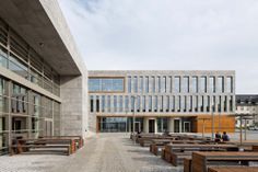 an empty courtyard with benches and tables in front of a building that has many windows