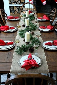 the table is set for christmas dinner with pine cones and red napkins on it