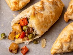 several pastries on a baking sheet with vegetables and meat in the middle, including carrots