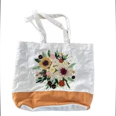 This White Canvas Tote Bag With Embroidered Floral Accents Is Perfect For Women Who Love To Travel Or For Casual Daily Use. The Bag Is Medium-Sized With A Height Of 14 Inches, Width Of 16.5 Inches, And A Depth Of 3.5 Inches. It Has An Inside Zipper Closure For Security And A Lightweight Inner Pocket For Easy Organization. The Tote Bag's Handle/Strap Is Made Of Cotton And Has A White Color, While The Handle Style Is Canvas. The Lining Is Made Of Cotton And Has A Green Color, And The Bag's Exterio Summer Tote Shoulder Bag With Embroidered Logo, Summer Beige Bag With Embroidered Logo, Summer Shoulder Bag With Embroidered Logo, Tote Style, Beige Embroidered Logo Bag For Summer, Spring Shopping Bag With Embroidery, Embroidered Bags For Spring Shopping, Spring Shopping Bags With Embroidery, Summer Shoulder Bag With Embroidered Logo For Daily Use, Embroidered Canvas Bag Casual Summer Style