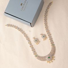 Description: This marvelous CZ long necklace set by Tarinika is as timeless as it is radiant. Both necklace and earrings display a beautiful arrangement of high-quality CZ stones, glittering brilliantly in the form of florals. Perfect to accentuate wedding outfits with an elegant touch, this necklace set can be combined with matching pieces of Tarinika CZ jewelry for a grand loyal look. Details & Specifications: Materials used: CZ Stone with White Gold Plating Weight - Necklace 74.75 gms, Earrin Elegant Stone Work Jewelry Sets For Party, Elegant Stone Work Jewelry Sets For Formal Occasions, Elegant Festive Jewelry Sets With Sparkling Stones, Elegant Formal Jewelry Sets With Stone Work, Festive Formal Crystal Jewelry Sets, Elegant Festive American Diamond Bridal Sets, Elegant Bridal Necklace With Stone Work In Cubic Zirconia, Elegant Bridal Necklace With Stone Work Cubic Zirconia, Elegant Bridal Necklace With Stone Work And American Diamond