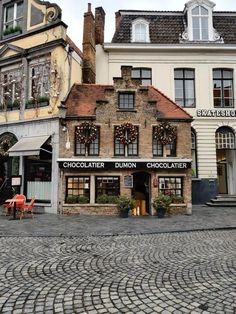 a cobblestone street in front of buildings with christmas decorations on the windows and shutters