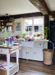 a kitchen filled with lots of white cabinets and flowers in vases on the counter