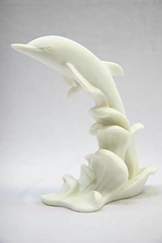 a white sculpture of two dolphins jumping out of the water with their mouths open, on a white background