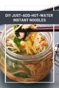 a jar filled with noodles and vegetables on top of a table