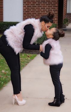 two women are kissing each other on the sidewalk in front of a brick building and grass