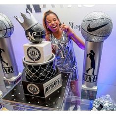 a woman standing in front of a cake made to look like basketballs on display