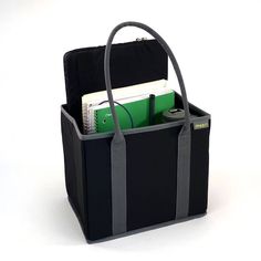 a black bag with grey straps and two books in the bottom compartment, sitting on a white surface