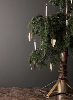 a small christmas tree with candles hanging from it's branches on a wooden table