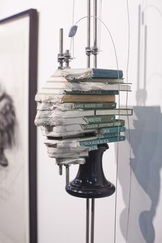 there is a lamp that has many books on it in front of a painting and pictures