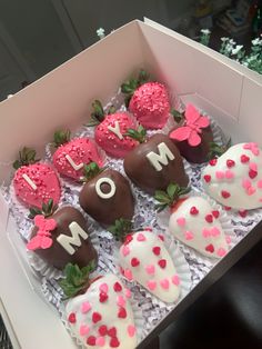 some chocolate covered strawberries in a box with pink and white frosting on them