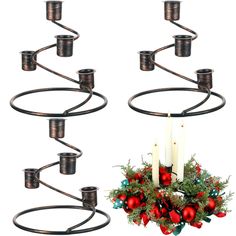 a christmas wreath with candles hanging from it's sides next to two metal candelabras