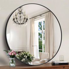 a mirror that is sitting on top of a dresser next to a vase with flowers