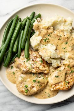 chicken with gravy, mashed potatoes and green beans on a plate