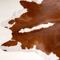 a brown and white cowhide rug on a white floor with no one in it