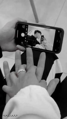 a person taking a photo with their cell phone while wearing a wedding band and ring