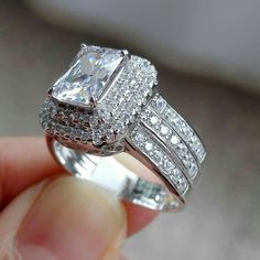 a person holding a diamond ring in their hand with the engagement ring on it's finger