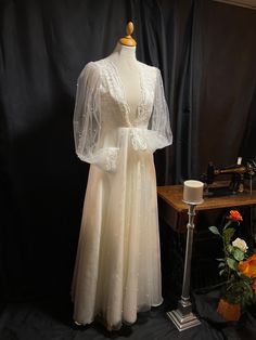 a dress on display in front of a black backdrop with flowers and an ironing board