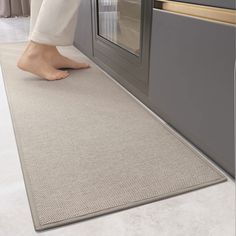 a person standing on the floor next to a kitchen counter top with a door open